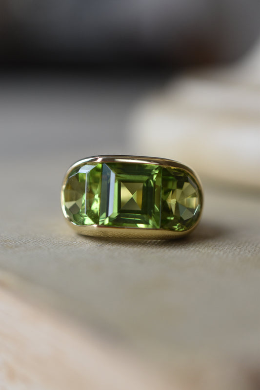 A Large Channel-set Peridot and Gold Trilogy Ring